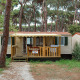 Solrig SunLodge Mobile Home Redwood ved Camping Village Capo d'Orso i Italien, omgivet af fyrretræer.