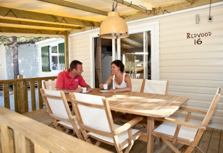 Par nyder kaffe på træterrasse ved SunLodge Mobile Home Redwood, Camping Village Capo d'Orso, Italien.