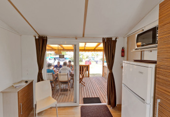 Vista interior de SunLodge Mobile Home Redwood en Camping Village Capo d'Orso con personas en la terraza.