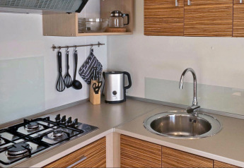 Moderne keuken in SunLodge Mobile Home Redwood op Camping Village Capo d'Orso, Italië met fornuis en gootsteen.