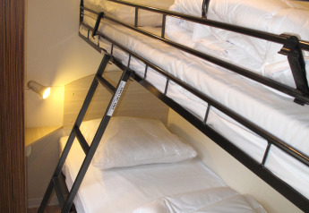 Letti a castello con lenzuola bianche e scala al SunLodge Mobile Home Aspen, Camping Village Capo d'Orso, Italia.