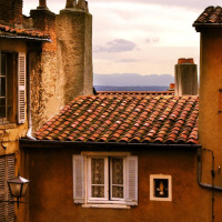 Photo of rustic tiled rooftops and old houses by the sea, captured at a holiday park offering glamping stays.