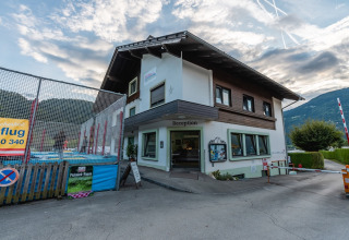 Außenansicht der Rezeption eines Ferienparks mit Bergen im Hintergrund, ideal für Glamping-Unterkünfte.