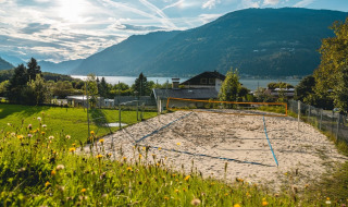 Cancha de voleibol de arena en un parque vacacional con glamping, con vistas al lago y montañas.