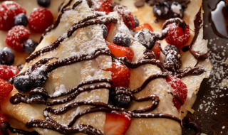 Deliciosos crepes con salsa de chocolate, frutos rojos frescos y un toque de azúcar glas.