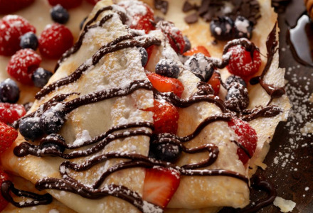 Delicious crepes drizzled with chocolate sauce, fresh berries, and dusted with powdered sugar.