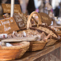 Puesto de mercado con cestas repletas de embutidos tradicionales y carteles escritos a mano en francés.