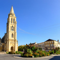 Foto pintoresca de una plaza con iglesia histórica, edificios a su alrededor y cielo azul despejado.