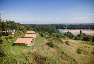 Safaritenten op een glooiende heuvel met uitzicht over de rivier bij Huttopia Saumur, Pays de la Loire, Frankrijk.