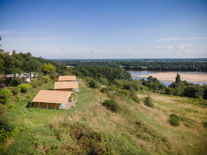 Safaritenten op een groene heuvel met uitzicht op de rivier bij Huttopia Saumur in Pays de la Loire, Frankrijk.