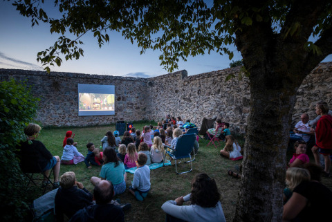 Familias y niños disfrutan de una noche de cine al aire libre en Huttopia Saumur, Pays de la Loire, Francia.