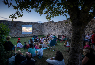Familias y niños disfrutan de una noche de cine al aire libre en Huttopia Saumur, Pays de la Loire, Francia.
