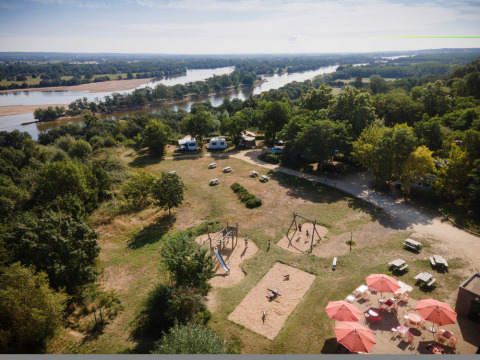 Vista aérea del parque vacacional Huttopia Saumur en Pays de la Loire, Francia, con área de juegos y río.