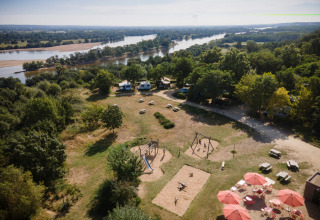 Luftaufnahme vom Ferienpark Huttopia Saumur in Pays de la Loire, Frankreich, mit Spielplatz und Fluss.