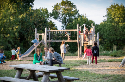 Enfants jouant sur une aire de jeux avec adultes à Huttopia Saumur, parc de vacances, Pays de la Loire, France.