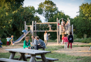 Bambini giocano in un parco giochi con adulti vicini, a Huttopia Saumur, Pays de la Loire, Francia.