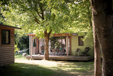 Cabaña con terraza de madera bajo árboles en Huttopia Saumur, un parque vacacional en Pays de la Loire, Francia.
