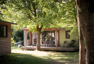 Vakantiehuis met terras tussen bomen bij Huttopia Saumur, vakantiepark in Pays de la Loire, Frankrijk.
