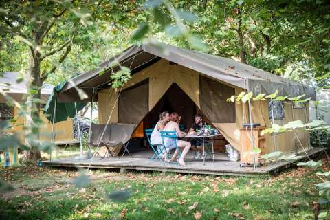 Vakantiegangers aan tafel voor een grote tent bij Huttopia Saumur, in Pays de la Loire, Frankrijk.