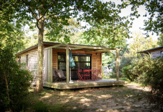 Houten huisje met schaduwrijke veranda op Huttopia Saumur vakantiepark in Pays de la Loire, Frankrijk.