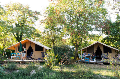 Dos tiendas lodge rodeadas de vegetación en Huttopia Saumur, un parque vacacional en Pays de la Loire, Francia.