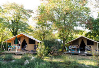 To hyggelige teltlodges i grønne omgivelser på Huttopia Saumur, et feriepark i Pays de la Loire, Frankrig.