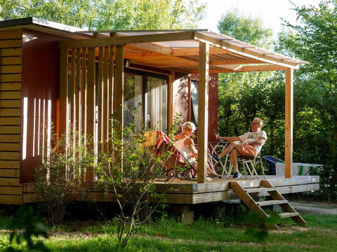 Pareja mayor relajándose en la terraza de una cabaña en Huttopia Saumur, Pays de la Loire, Francia.