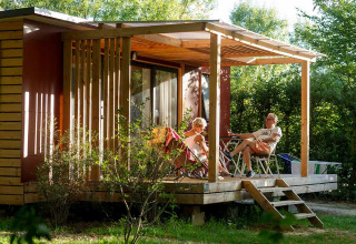 Older couple relaxing on the porch of a cabin at Huttopia Saumur holiday park in Pays de la Loire, France.