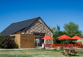Buitencafé met kleurrijke parasols bij Huttopia Saumur vakantiepark in Pays de la Loire, Frankrijk.