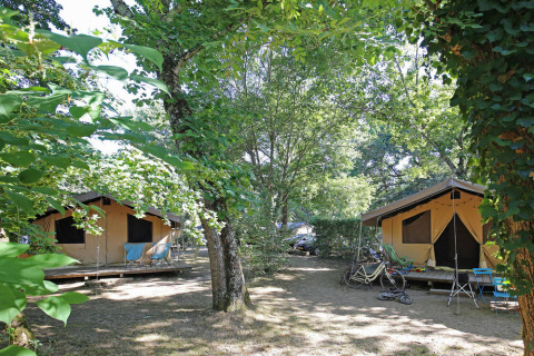 Toile&Bois safari tent Sweet in een bosrijke omgeving met fietsen en stoelen buiten de tenten.