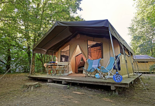 Safari tent Toile&Bois Sweet op houten terras in het bos, met stoelen en ontspannen sfeer.