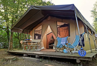 Toile&Bois Safari Tent Sweet met houten terras, stoelen en tafel buiten, omgeven door groene bomen.