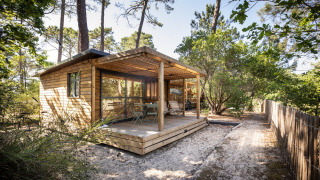 Chalet in legno presso Chalet Evasion con veranda immersa nella natura per un soggiorno glamping rilassante.