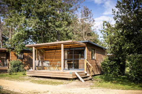 Vista exterior del alojamiento glamping Chalet Evasion, una acogedora cabaña de madera entre árboles.