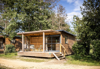 Buitenaanzicht van de Chalet Evasion glamping accommodatie, een knusse houten cabin tussen bomen.