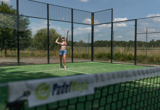Een vrouw speelt padel op een buitenbaan bij Village Huttopia Lac de Rillé, Centre-Val de Loire, Frankrijk.