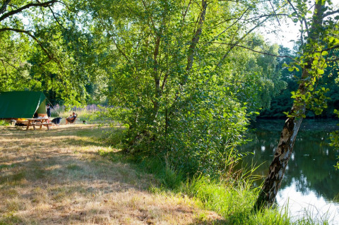 Camping au bord du lac avec arbres verts à Huttopia Lac de Rillé, Centre-Val de Loire, France.