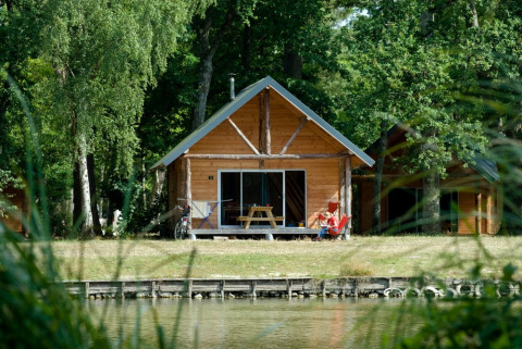 Cabaña de madera junto al lago en Village Huttopia Lac de Rillé, rodeada de bosque en Centre-Val de Loire, Francia