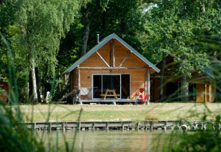 Houten hut aan het meer in Village Huttopia Lac de Rillé, omgeven door bossen in Centre-Val de Loire, Frankrijk