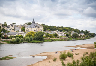 Panoramisch uitzicht op een dorp aan de rivier met kerk en mensen op het zandstrand in Centre-Val de Loire, Frankrijk.