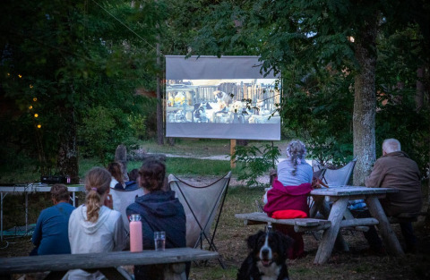 Huéspedes ven una película al aire libre en Village Huttopia Lac de Rillé, un parque vacacional en Francia.