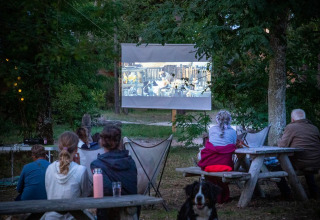 Bezoekers genieten van een openluchtfilmavond in Village Huttopia Lac de Rillé, een vakantiepark in Frankrijk.