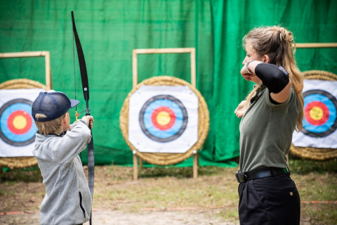A woman and a child practice archery at targets in Village Huttopia Lac de Rillé holiday park, France.