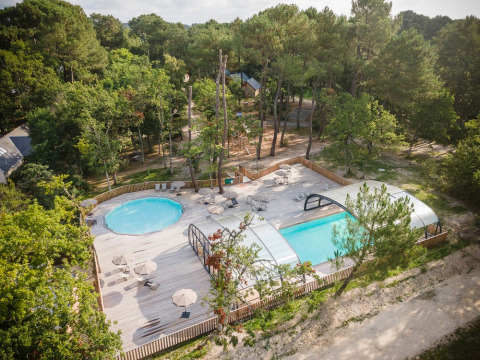 Vista aérea de la zona de piscina en Village Huttopia Lac de Rillé, rodeada de bosque en Centre-Val de Loire, Francia.