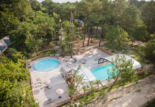 Luchtbeeld van het zwembad aan Village Huttopia Lac de Rillé, omgeven door bos in Centre-Val de Loire, Frankrijk.