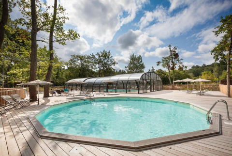 Piscina exterior con terraza de madera y tumbonas en Village Huttopia Lac de Rillé, Centro-Val de Loire, Francia.