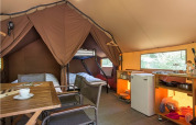 Innenansicht eines gemütlichen Canadienne-Safari-Zeltes mit Betten, Küchenecke und Esstisch in Huttopia Lac de Rillé.