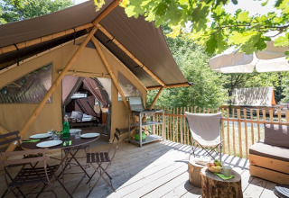 Tienda safari Canadienne en Village Huttopia Lac de Rillé, Francia, con terraza de madera amueblada y vista natural.
