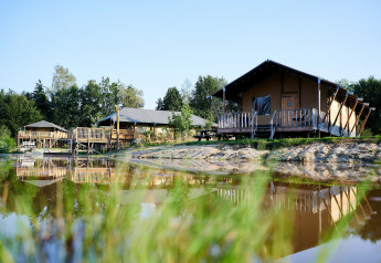 Tiendas safari de lujo junto al agua en Holiday Park Sallandshoeve, Países Bajos, rodeadas de naturaleza.