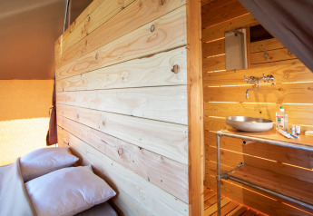 Vista interior de Tente Trappeur Duo Village en Huttopia Lac de Rillé, con cama y baño de madera.